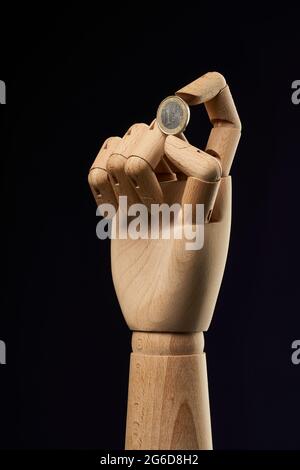 pièce de 2 euros en main en bois sur fond noir en studio montrant le concept de finance Banque D'Images