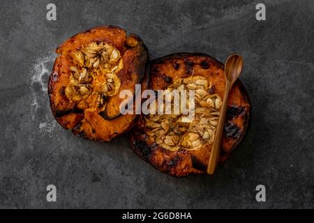 De dessus de savoureux appétissant des demi-citrouilles cuites au four avec des graines sur la table grise Banque D'Images