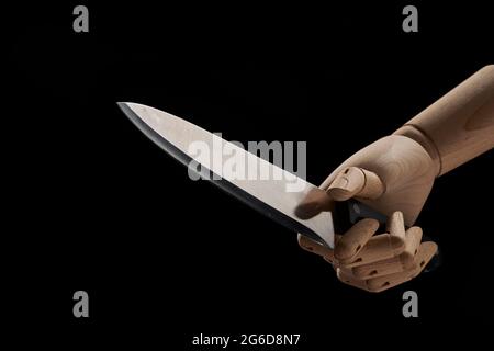 Couteau pointu dans une main en bois en studio sur fond noir démontrant le concept de violence Banque D'Images