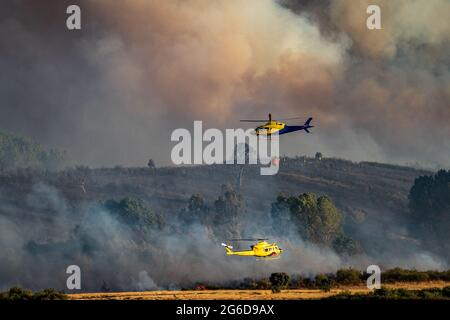 Deux hélicoptères, bambi seau et pompiers en arrière-plan Banque D'Images