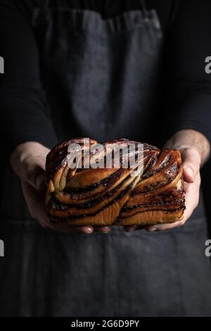 Crop-man méconnaissable en tablier noir debout avec dessert Babka au chocolat maison Banque D'Images