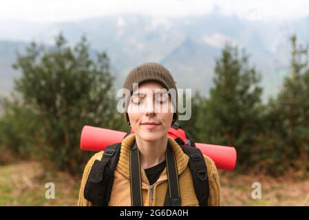 Une randonneur femelle insouciante se tenant dans les montagnes avec les yeux fermés et appréciant la nature pendant le voyage en été Banque D'Images