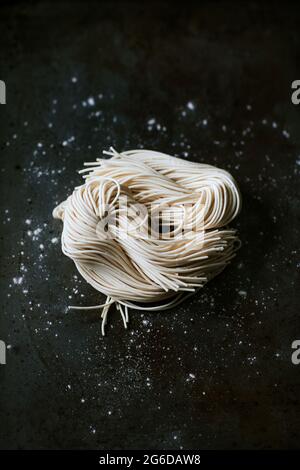 Vue de dessus des nouilles non cuites pour la préparation de ramen sur fond sombre Banque D'Images
