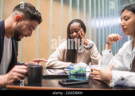 Compagnie de divers collègues se rassemblant à table dans la cuisine et ayant la pause tout en mangeant le déjeuner Banque D'Images
