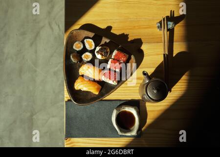 De l'assiette ci-dessus avec un assortiment de petits pains à sushis servis sur une table avec des baguettes et de la sauce soja dans le restaurant japonais Banque D'Images