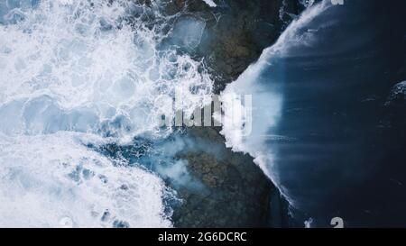 Vue de drone sur un paysage à couper le souffle de vagues de mer mousseuse qui s'écrasant sur un bord de mer rocailleux Banque D'Images