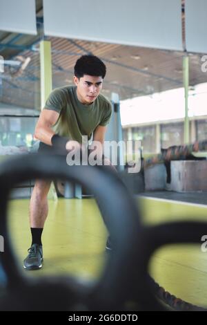 Entraînement d'homme asiatique concentré avec corde de combat dans un gymnase crossfit moderne Banque D'Images