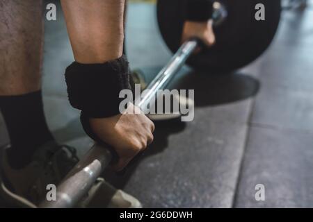 Court sportif masculin non reconnaissable faisant levée de mort avec une barbell lourde pendant l'entraînement dans la salle de gym Banque D'Images