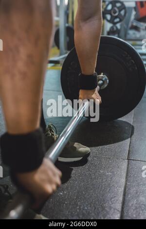 Court sportif masculin non reconnaissable faisant levée de mort avec une barbell lourde pendant l'entraînement dans la salle de gym Banque D'Images