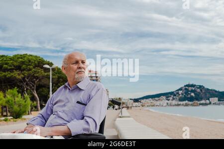 Homme senior en fauteuil roulant sur la promenade, avec vue sur la contemplation et la vue sur la mer Banque D'Images