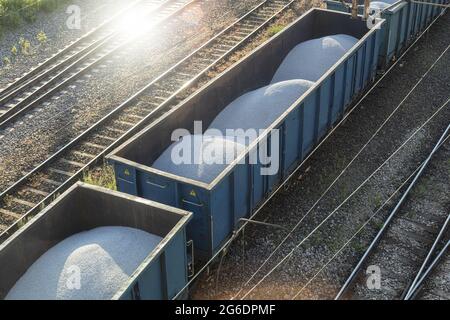 Les wagons de chemin de fer chargés se déplacent sur des rails. Train de marchandises avec gravier blanc, vue de dessus Banque D'Images