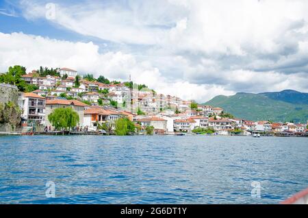 Magnifique vue depuis le lac avec des bateaux, des pierres, une plage, une montagne sur un ciel bleu clair Banque D'Images