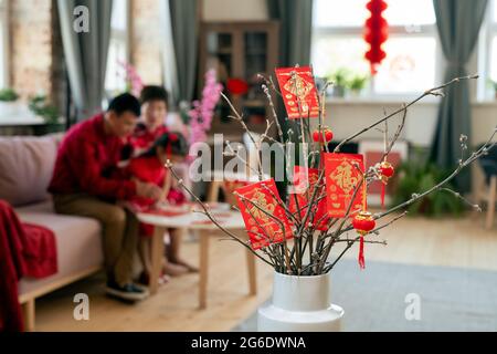 Cartes postales et lanternes chinoises rouges du nouvel an accrochées à des branches sèches dans un vase blanc Banque D'Images