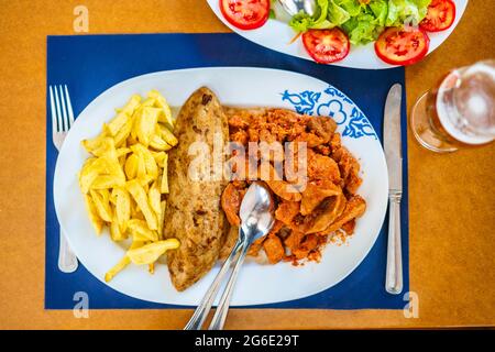 Cuisine traditionnelle de l'Alentejo, la langue de la vache dans une sauce servie avec de la salade, du riz et des frites, Portugal Banque D'Images