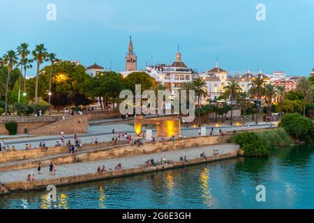 Front de mer Muelle de la sal à la rivière Rio Guadalquivir avec Monumento a la Tolerancia, à l'arrière la Giralda, heure bleue, Séville, Andalousie, Espagne Banque D'Images