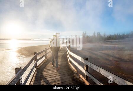 Randonneur sur la promenade entre les sources chaudes, le soleil du matin, West Thumb Geyser Basin, parc national de Yellowstone, Wyoming, États-Unis Banque D'Images