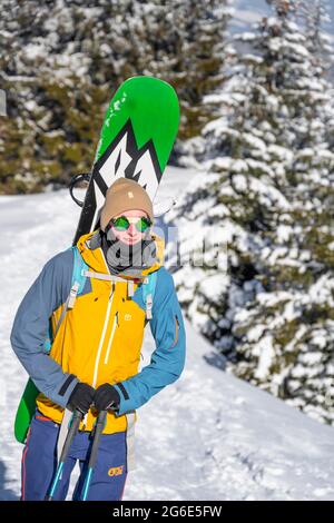 Jeune homme avec surf des neiges sur le dos, ski tourer en tournée à Teufelstaettkopf, Alpes d'Ammergau, Unterammergau, Bavière, Allemagne Banque D'Images