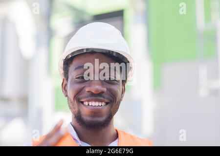 Jeune homme noir travaillant dehors comme technicien avec casque et gilet de sécurité, Fribourg, Bade-Wurtemberg, Allemagne Banque D'Images