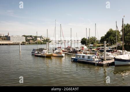 Divers bateaux sont amarrés au port d'un petit village de pêcheurs sur la Loire, avec vue sur Nantes en arrière-plan, à Reze, Loire-Atlantique, France. Banque D'Images