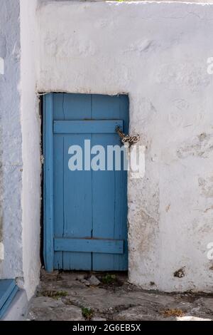 Cyclades Grèce. Petite porte bleue sur un mur blanchi à la chaux. Maison blanche typique, entrée fermée à clé sur l'île de Kimolos, village Chora Chorio. Par Banque D'Images