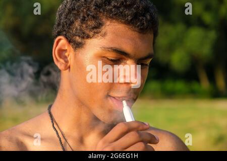 Gros plan afro-américain jeune homme vaporisant de l'e-cigarette avec de l'e-liquide Banque D'Images