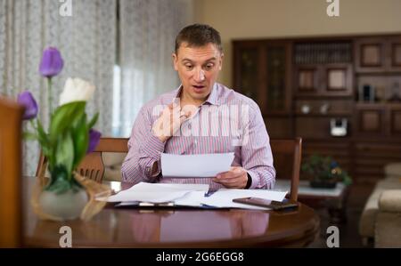 Triste homme frustré à à bout de papier à la table Banque D'Images