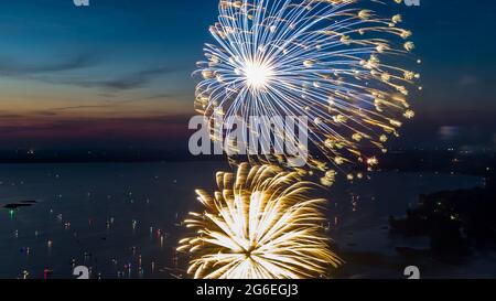 Feu d'artifice le quatrième juillet tiré d'une barge sur un lac pris avec un drone. Banque D'Images