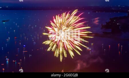 Feu d'artifice le quatrième juillet tiré d'une barge sur un lac pris avec un drone. Banque D'Images