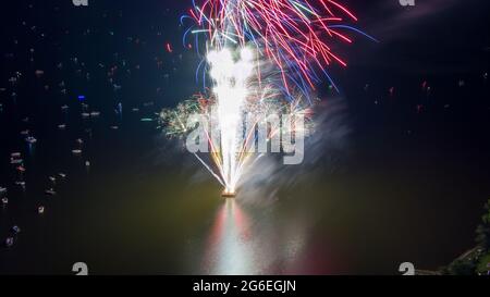 Feu d'artifice le quatrième juillet tiré d'une barge sur un lac pris avec un drone. Banque D'Images