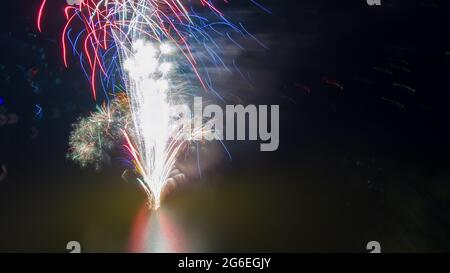 Feu d'artifice le quatrième juillet tiré d'une barge sur un lac pris avec un drone. Banque D'Images