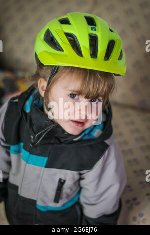 Toddle enfant qui débarque sa moto dans un casque vert Banque D'Images