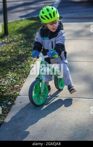 Toddle enfant qui débarque sa moto dans un casque vert Banque D'Images