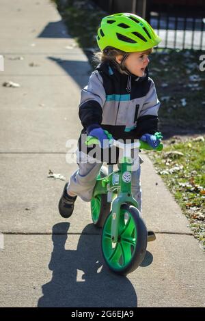 Toddle enfant qui débarque sa moto dans un casque vert Banque D'Images