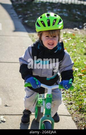 Toddle enfant qui débarque sa moto dans un casque vert Banque D'Images