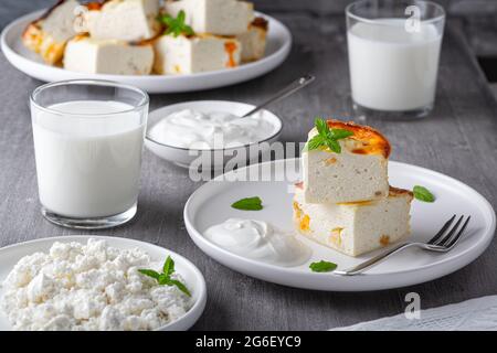 Cocotte de fromage cottage avec raisins secs et tasse de lait sur fond gris en bois. Cocotte de fromage cottage Banque D'Images