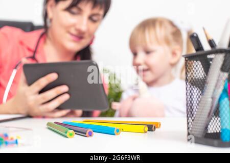 Femme enfant médecin montre des dessins animés sur la tablette à une petite fille de 4 ans. Le concept de l'approche des médecins à l'égard des enfants Banque D'Images