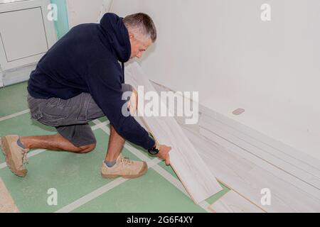 Un travailleur qui relie le plancher stratifié pendant la rénovation de la maison. Banque D'Images