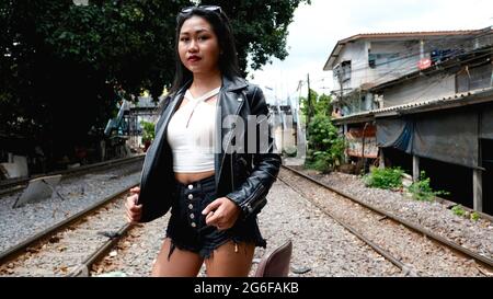 Chemin de fer de style des années 1950 avec modèle asiatique de mode féminin chinois debout par les pistes Bangkok Thaïlande Banque D'Images