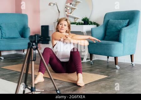 Flexible attirante femme sportive faisant de la gymnastique devant le téléphone et l'enregistrement vidéo. Enregistrez vos séances de yoga sur l'appareil photo du téléphone ou diffusez-les sur des socia Banque D'Images