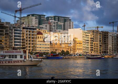 Coucher de soleil sur la ville de Sliema à Malte, vue sur la ligne d'horizon depuis le port de Marsamxett dans la mer Méditerranée. Banque D'Images