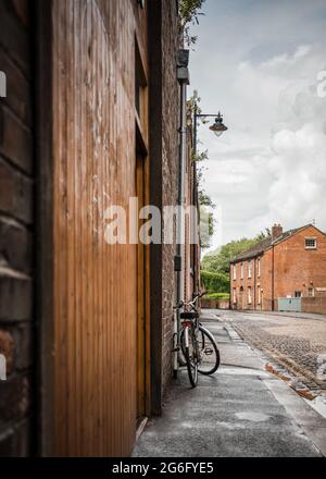 Vélo se penchant contre le mur sur la vieille rue industrielle arrière avec des ruelles pavées, des cottages et des bâtiments d'usine anciens. Le vélo ne se penchait pas sur les paysages Banque D'Images