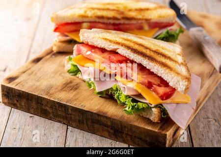 Sandwich avec tomate, laitue, jambon et fromage sur une table en bois Banque D'Images