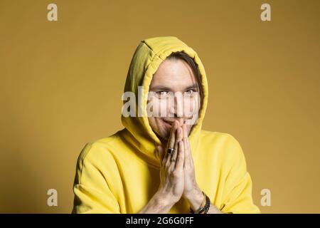 Portrait de l'homme excité en sweat-shirt à capuche jaune Banque D'Images