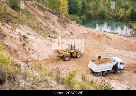 Big Yellow de camions à benne travaillant dans la mine à ciel ouvert. Transport de sable et de minéraux. Carrière minière pour la production de pierre concassée, sable et gravier pour Banque D'Images