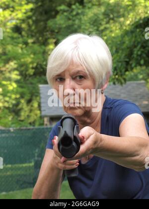 Femme tenant un grand fusil de chasse semblant repousser toute menace. Femme confiante tenant l'arme d'une manière intimidante suggestion légitime défense. Banque D'Images