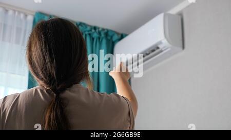 Une femme méconnaissable allume le climatiseur, vue arrière. Banque D'Images