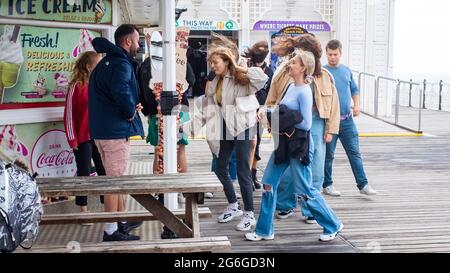 Brighton Royaume-Uni 6 juillet 2021 - les visiteurs se battent contre les vents forts sur la jetée de Brighton avec des rafales de prévisions de jusqu'à 40 miles par heure pour certaines régions : crédit Simon Dack / Alamy Live News Banque D'Images