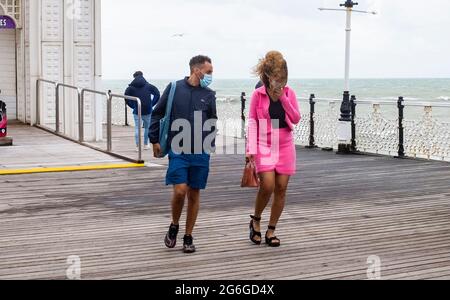 Brighton Royaume-Uni 6 juillet 2021 - les visiteurs se battent contre les vents forts sur la jetée de Brighton avec des rafales de prévisions de jusqu'à 40 miles par heure pour certaines régions : crédit Simon Dack / Alamy Live News Banque D'Images