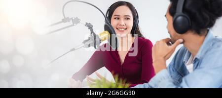 Deux hôtes asiatiques radio enregistrement podcast dans le studio de diffusion, femme asiatique parlant sur le microphone avec l'homme en ligne à la maison. Banque D'Images