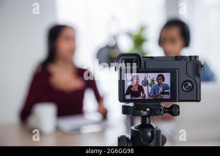 Gros plan caméra de deux hôtes de radio asiatiques enregistrant le podcast dans le studio de diffusion, femme asiatique parlant sur le microphone avec l'homme en ligne à la maison Banque D'Images